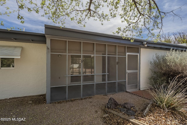 rear view of property with a sunroom and stucco siding