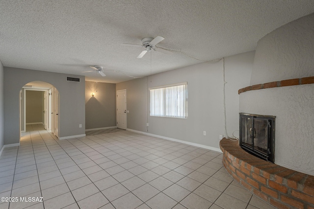 unfurnished living room featuring arched walkways, light tile patterned floors, visible vents, and a ceiling fan
