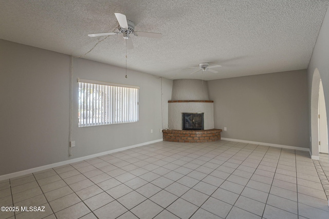 unfurnished living room featuring a ceiling fan, baseboards, a fireplace, and a textured ceiling