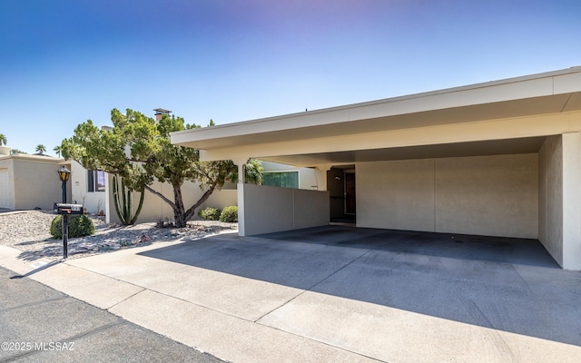 view of front of property with a carport, fence, and stucco siding