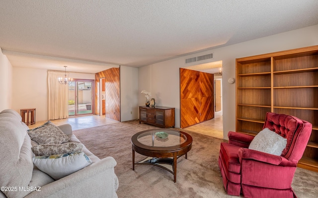 carpeted living area with visible vents, an inviting chandelier, and a textured ceiling