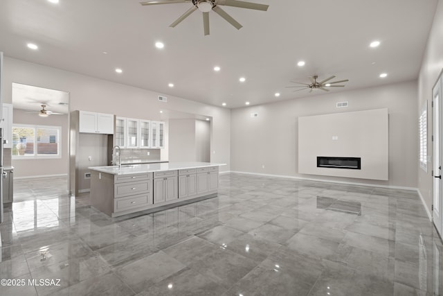 2891 N Wentworth Rd, Tucson, AZ 85749 - unfurnished living room featuring visible vents, baseboards, ceiling fan, recessed lighting, and a glass covered fireplace