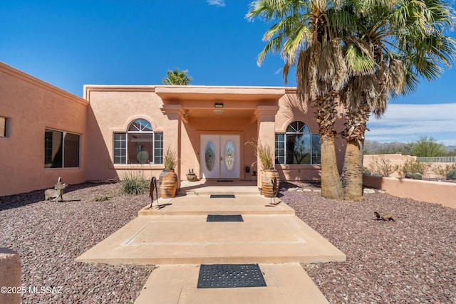 view of exterior entry featuring french doors and stucco siding