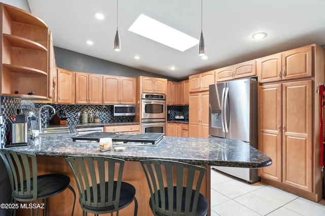 kitchen with tasteful backsplash, stainless steel appliances, a sink, vaulted ceiling with skylight, and a peninsula
