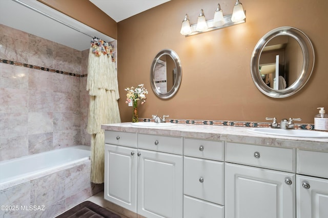 bathroom featuring double vanity, a sink, and tiled shower / bath