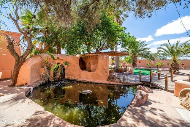 exterior space with a fenced backyard and a garden pond