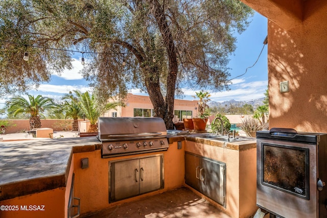 view of patio featuring a grill, area for grilling, fence, and a sink
