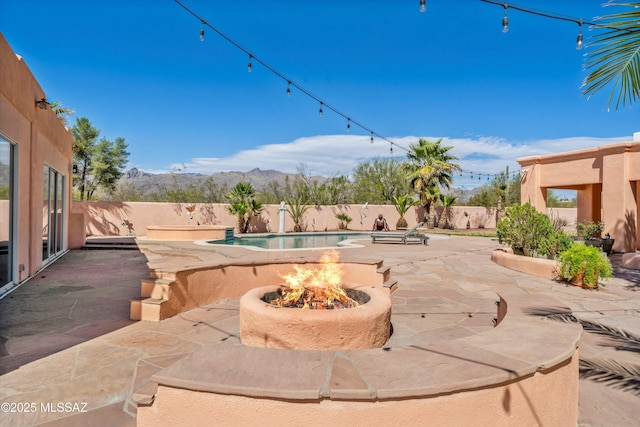 view of patio / terrace featuring a fenced backyard, a fire pit, a mountain view, and a fenced in pool
