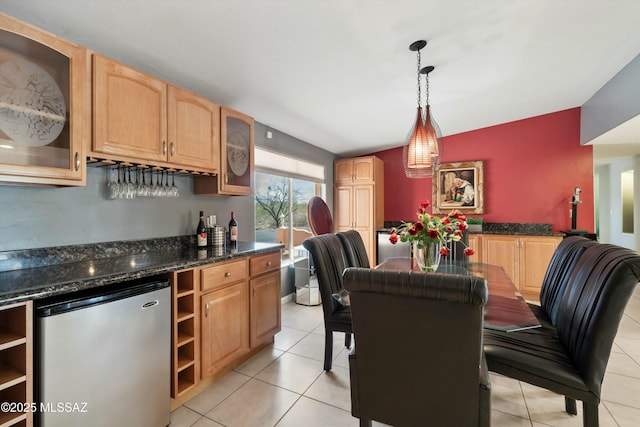 kitchen featuring fridge, light brown cabinetry, light tile patterned flooring, pendant lighting, and glass insert cabinets