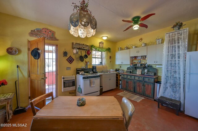 kitchen with a sink, heating unit, white appliances, ceiling fan, and white cabinets