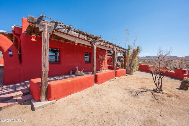 view of side of property featuring fence, a mountain view, and stucco siding