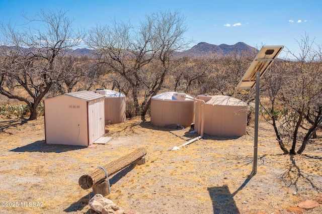 view of yard featuring a storage unit, an outbuilding, and a mountain view