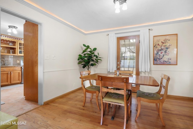 dining space featuring crown molding, baseboards, and light wood-type flooring