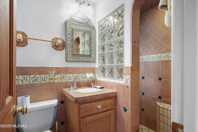 half bath with tile walls, toilet, and vanity
