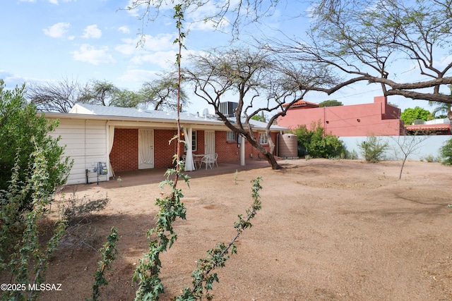 rear view of property featuring brick siding, central AC, fence, and a patio