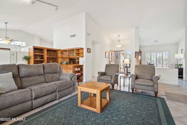 tiled living room featuring track lighting, arched walkways, a ceiling fan, vaulted ceiling, and visible vents