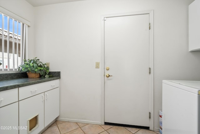 clothes washing area featuring light tile patterned floors, washer / dryer, and cabinet space