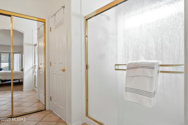 ensuite bathroom with ensuite bathroom, tile patterned floors, and a stall shower