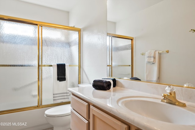 bathroom featuring toilet, vanity, and combined bath / shower with glass door