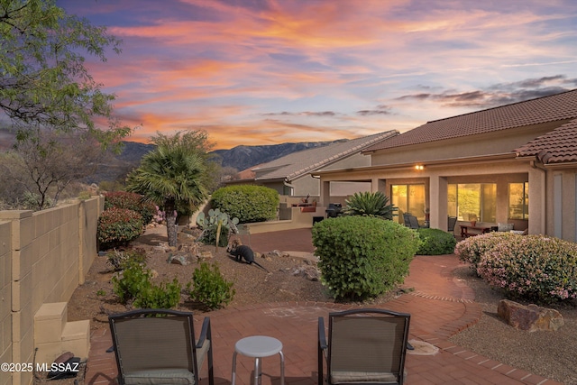 patio terrace at dusk with a mountain view and fence