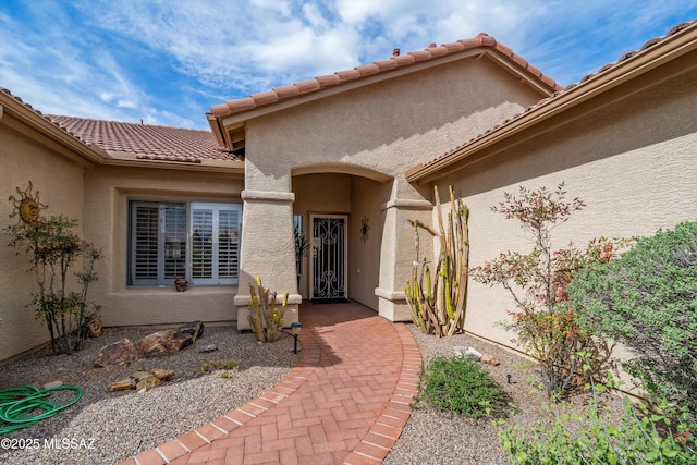 view of exterior entry featuring stucco siding and a tiled roof