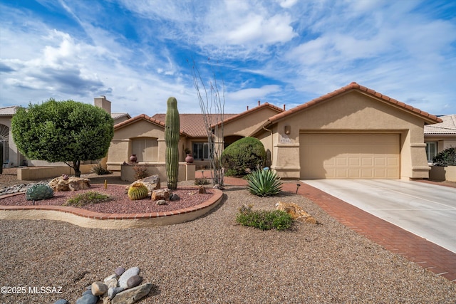 view of front of house with driveway, stucco siding, a tile roof, and a garage