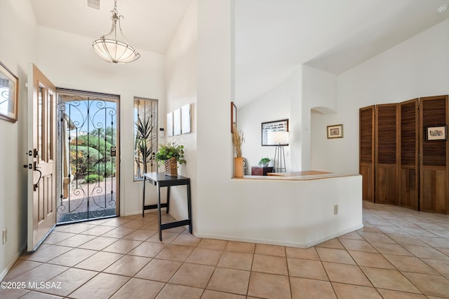 entrance foyer with arched walkways, high vaulted ceiling, and light tile patterned floors