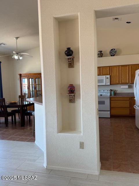 4769 S Meadow Ridge Dr, Green Valley, AZ 85622 - kitchen with white appliances, a ceiling fan, light tile patterned floors, brown cabinetry, and light countertops