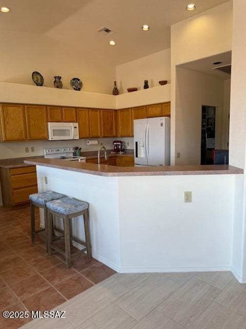4769 S Meadow Ridge Dr, Green Valley, AZ 85622 - kitchen featuring white appliances, brown cabinetry, a kitchen breakfast bar, a sink, and recessed lighting