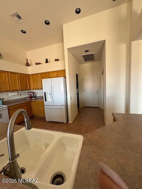 4769 S Meadow Ridge Dr, Green Valley, AZ 85622 - kitchen with white appliances, brown cabinetry, a sink, and recessed lighting