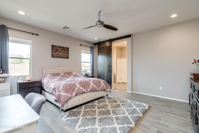 bedroom featuring wood finished floors, multiple windows, and a barn door