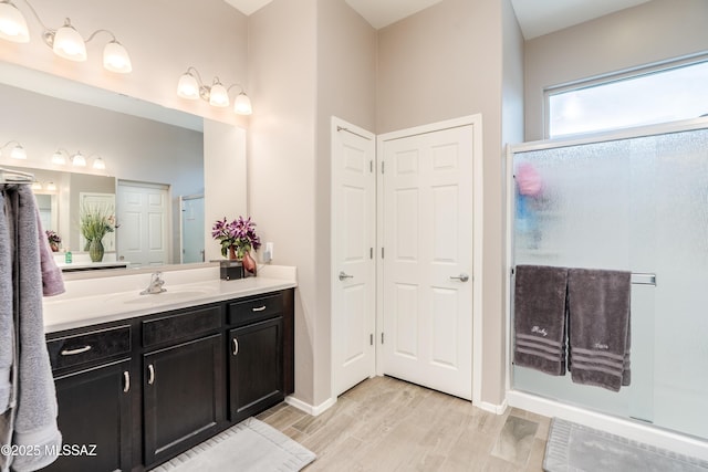full bath with vanity, baseboards, a stall shower, and wood finished floors
