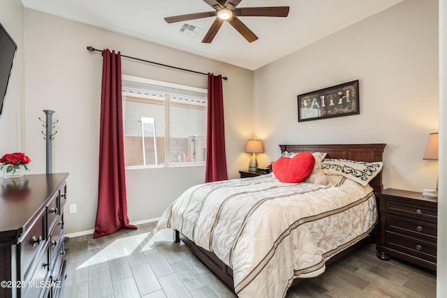 bedroom featuring wood finished floors, baseboards, a ceiling fan, and visible vents