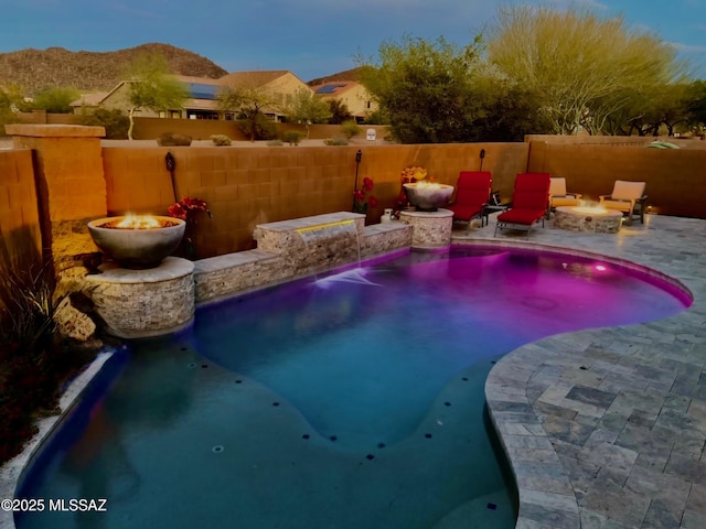 view of pool with a mountain view, an outdoor fire pit, fence, a patio, and a fenced in pool