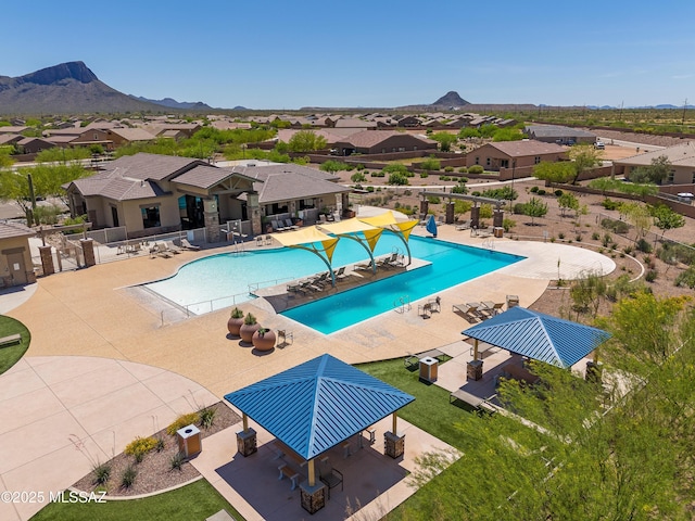 community pool featuring a mountain view, fence, a patio, and a residential view
