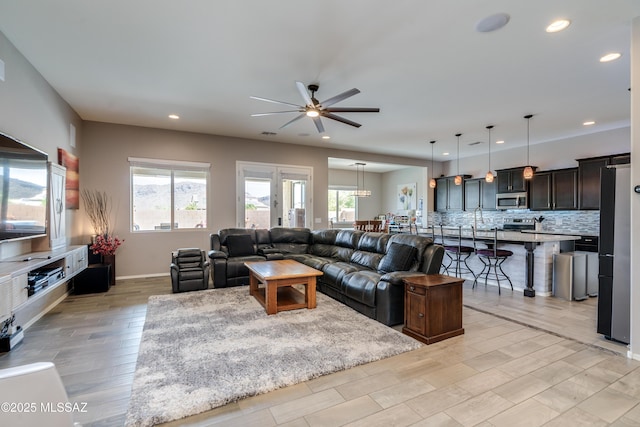 living room with ceiling fan, recessed lighting, baseboards, and light wood finished floors