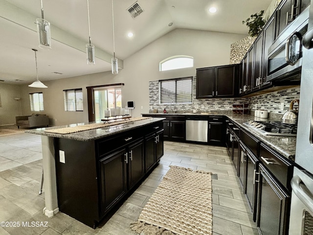 8754 W Denstone Rd, Marana, AZ 85653 - kitchen with dark cabinets, stainless steel appliances, a kitchen island, decorative backsplash, and plenty of natural light