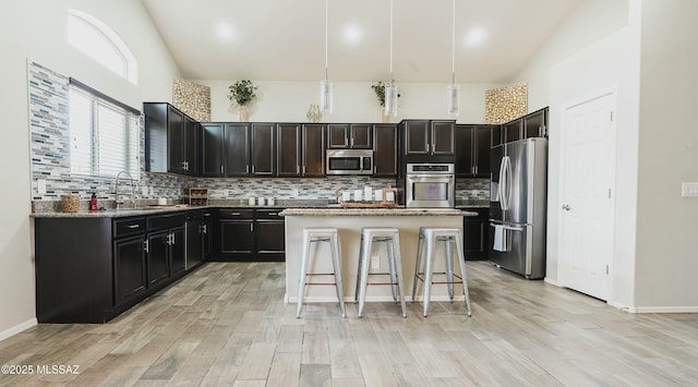 8754 W Denstone Rd, Marana, AZ 85653 - kitchen with stainless steel appliances, decorative backsplash, a sink, light wood finished floors, and a center island