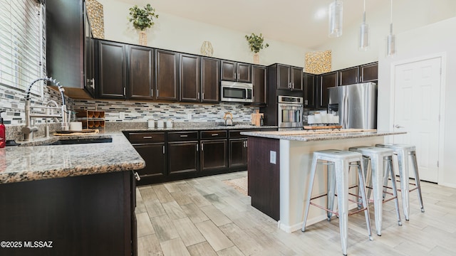8754 W Denstone Rd, Marana, AZ 85653 - kitchen with stainless steel appliances, a sink, tasteful backsplash, light stone countertops, and a kitchen bar