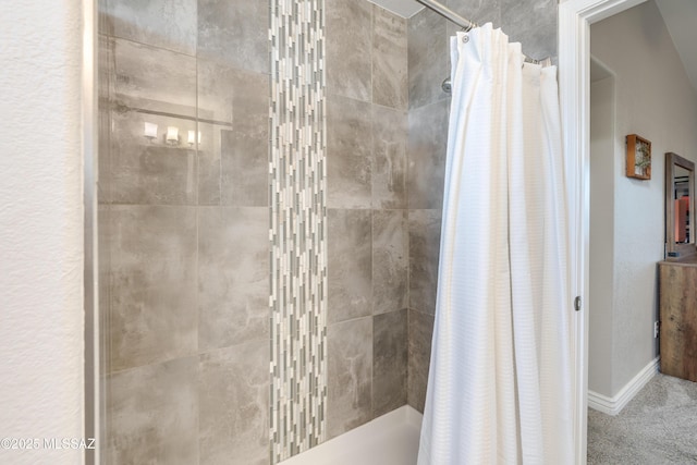 bathroom featuring baseboards and tiled shower
