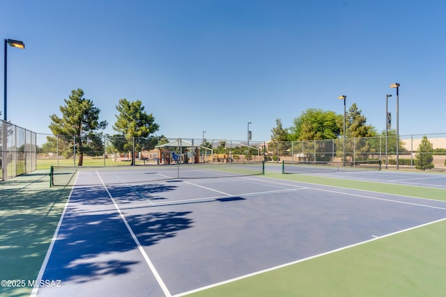 view of tennis court featuring community basketball court and fence