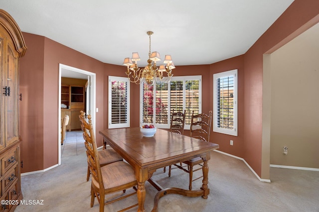 dining area with baseboards, a notable chandelier, and light colored carpet