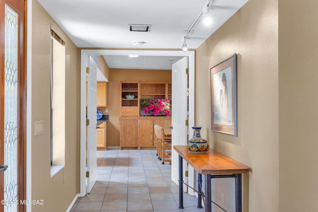 hall with rail lighting, light tile patterned floors, and baseboards