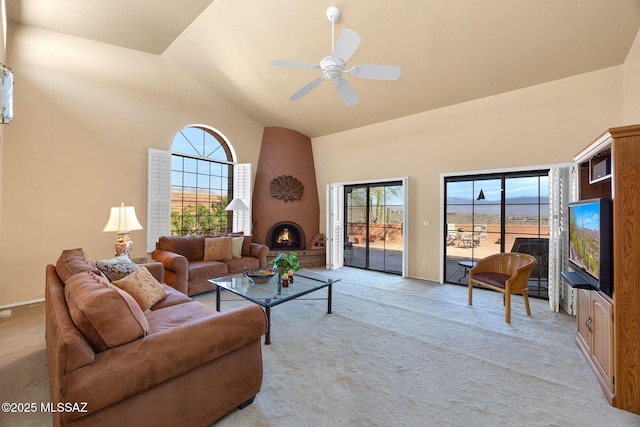 living area featuring high vaulted ceiling, a ceiling fan, light carpet, and a fireplace