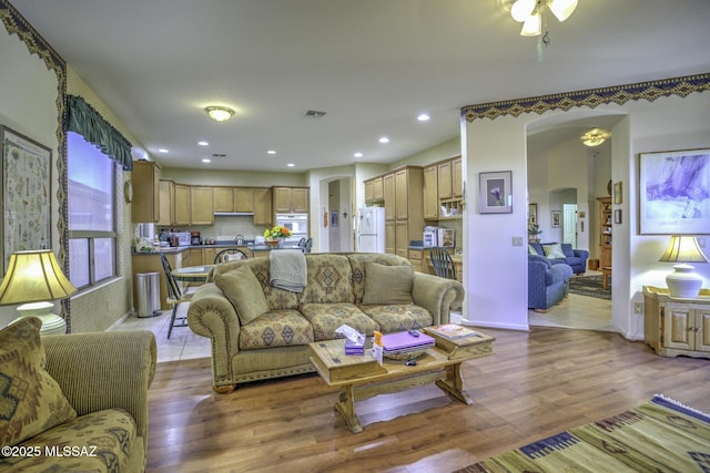 62583 E Amberwood Dr, Saddlebrooke, AZ 85739 - living area with light wood-type flooring, visible vents, arched walkways, and ceiling fan