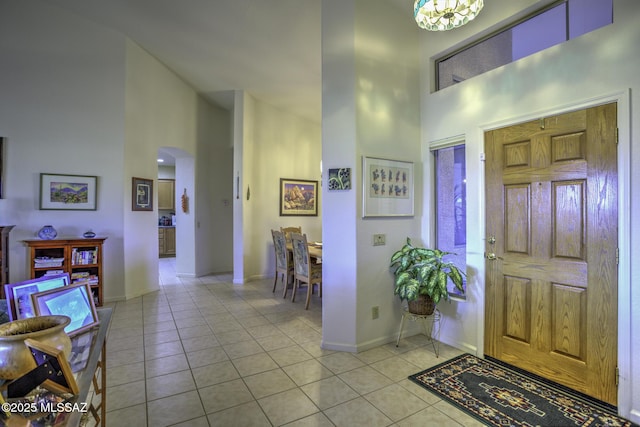 62583 E Amberwood Dr, Saddlebrooke, AZ 85739 - foyer entrance featuring arched walkways, baseboards, a high ceiling, and light tile patterned floors