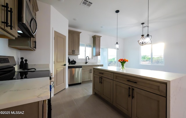 1686 Circulo Bahia, Rio Rico, AZ 85648 - kitchen featuring stainless steel appliances, a sink, decorative light fixtures, a center island, and light stone counters