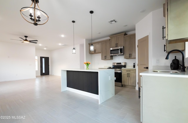 1686 Circulo Bahia, Rio Rico, AZ 85648 - kitchen with appliances with stainless steel finishes, a sink, a kitchen island, decorative light fixtures, and light countertops