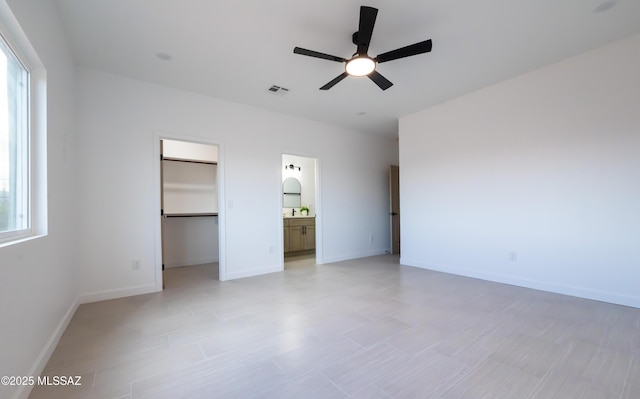 1686 Circulo Bahia, Rio Rico, AZ 85648 - unfurnished bedroom with a spacious closet, baseboards, a closet, ceiling fan, and connected bathroom
