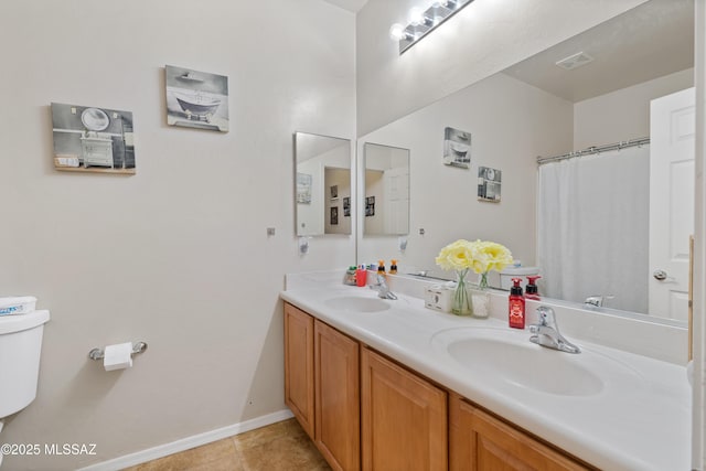 full bath with toilet, a sink, double vanity, and tile patterned flooring